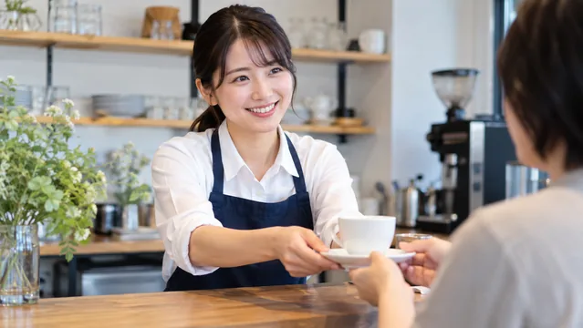 カフェでカップを手渡す人物（生成イメージ）